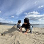 砂浜を歩く子供たちと歌手・山口沙織